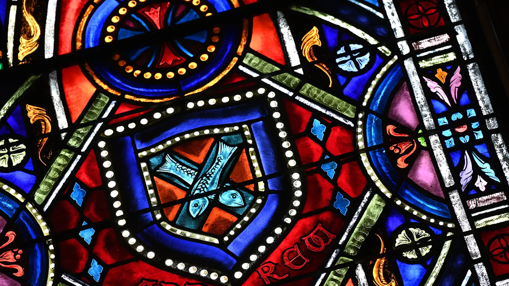 stained glass close up showing fish in a cross