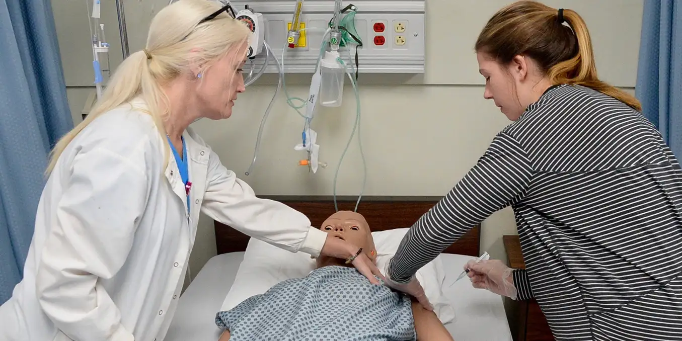 Belhaven nursing professor working with student on an educational dummy